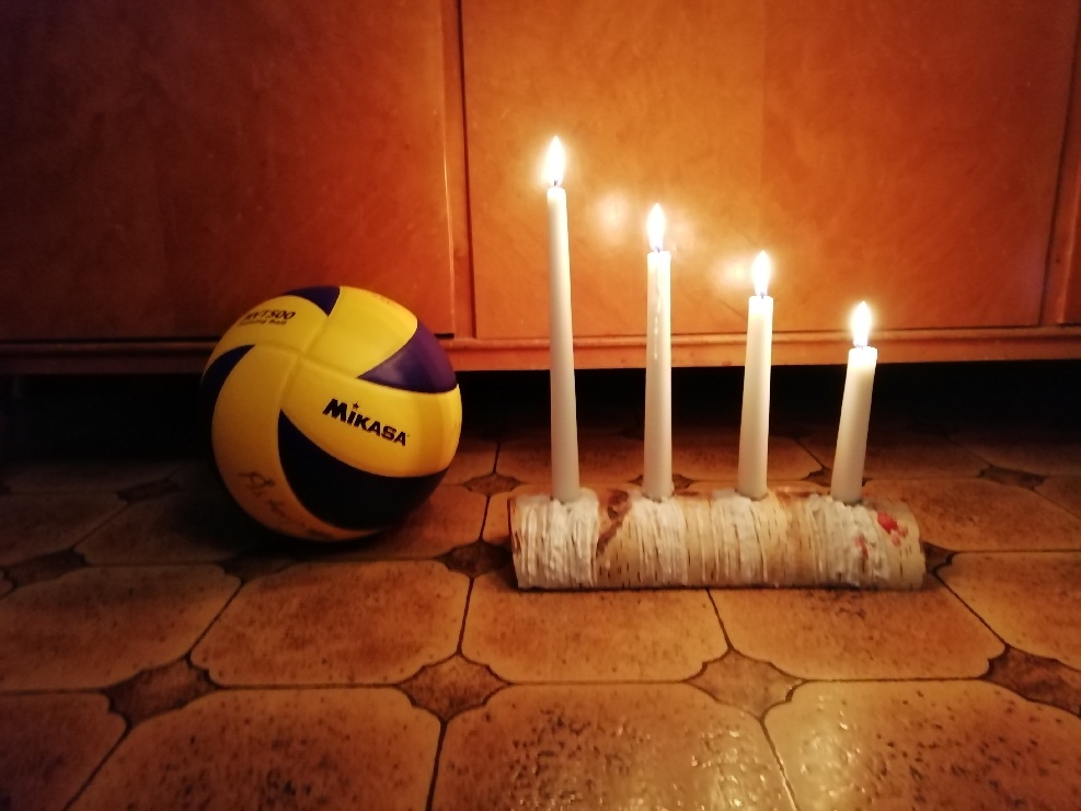 En volleyboll bredvid en adventsljusstake med fyra tända ljus. Foto: Göran Henrysson
